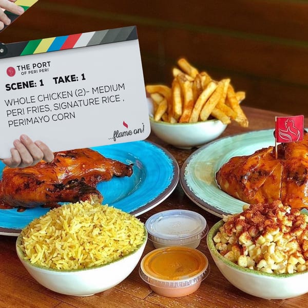 Two whole peri-peri chickens, fries, rice, and corn, with a clapperboard overlay.